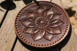 Brown leather coaster with floral design on a wooden surface